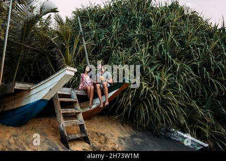 Hochzeitsreise. Verliebtes Paar am Meer, das Kokosnuss trinkt. Pärchen am Ufer der Paradise Island. Mann und Frau auf Bali. Entspannen Sie sich auf der Insel Stockfoto