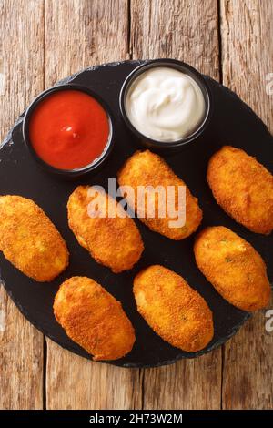 Salz Kabeljau Kroketten croquetas de bacalao mit Saucen schließen sich in der Schieferplatte auf dem Tisch. Vertikale Draufsicht von oben Stockfoto