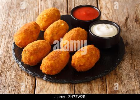 Cremig gesalzene Kabeljau Kroketten Croquetas De Bacalao Nahaufnahme in der Schieferplatte auf dem Tisch. Horizontal Stockfoto