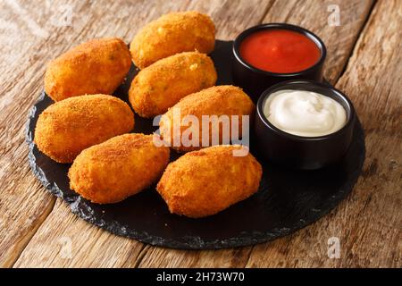 Baskische goldene Kabeljau-Kroketten Croquetas De Bacalao mit Saucen in der Schieferplatte auf dem Tisch aus nächster Nähe. Horizontal Stockfoto