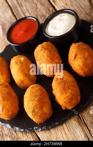 Salz Kabeljau Kroketten croquetas de bacalao mit Saucen schließen sich in der Schieferplatte auf dem Tisch. Vertikal Stockfoto