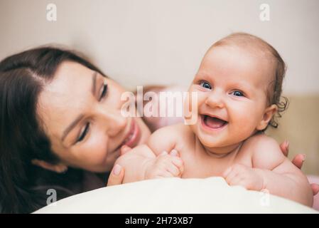 Glücklich lachendes Baby, das Zeit mit seiner Mutter in der Wohnung verbringt Stockfoto