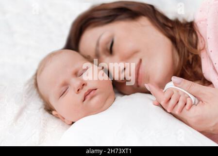 Mama hält sanft die kleine Hand ihrer schlafenden kleinen Tochter im Schlafzimmer Stockfoto