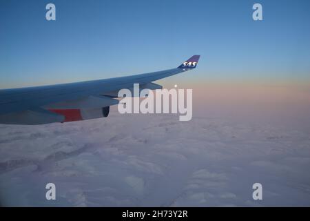 KOPENHAGEN, DÄNEMARK - 24. NOV 2018: Blick von der Flugzeugkabine auf den Flügel bei Sonnenuntergang über die Eisberge Grönlands Stockfoto