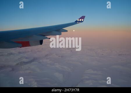 KOPENHAGEN, DÄNEMARK - 24. NOV 2018: Blick von der Flugzeugkabine auf den Flügel bei Sonnenuntergang über die Eisberge Grönlands Stockfoto