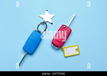 Autoschlüssel mit Plastikanhänger und Schlüsselanhänger auf blauem Hintergrund Stockfoto