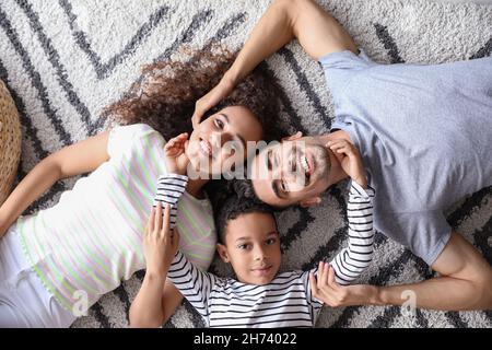 Glückliche interrassische Familie, die auf dem Teppich lag, Draufsicht Stockfoto