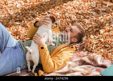 Schöner Mann mit witzigem Jack Russel Terrier im Park am Herbsttag Stockfoto