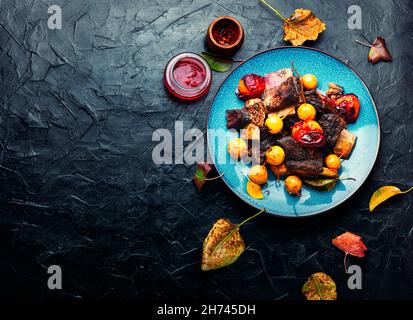 In Pflaumen und Birnen gebackene Rinderrippen.in Obstsoße gegrillte Fleischrippen auf dem Teller.Platz kopieren Stockfoto