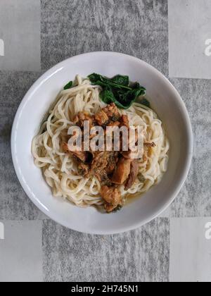 Vertikale Aufnahme einer köstlichen Nudelschüssel mit Huhn und Gemüse darauf Stockfoto