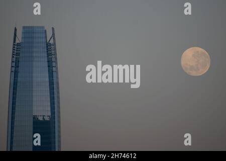 Santiago, Metropolitana, Chile. 20th. November 2021. Der Vollmond im November, der Bibermond, geht bei Sonnenaufgang in Santiago, Chile, neben dem Costanera-Gebäude unter. (Bild: © Matias Basualdo/ZUMA Press Wire) Stockfoto