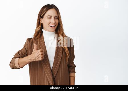 Erfolgreiche Geschäftsfrau, Verkäuferin winkend und lächelnd, zeigt Daumen nach oben in Zustimmung, loben Sie, Kompliment Unternehmen, weißer Hintergrund Stockfoto