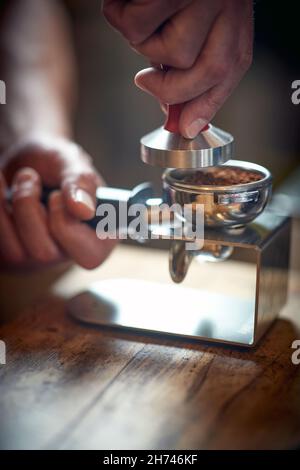 Nahaufnahme der Hände eines Barkeepers mit Zubehör für die Zubereitung eines aromatischen und duftenden Espresso. Kaffee, Getränke, Bar Stockfoto