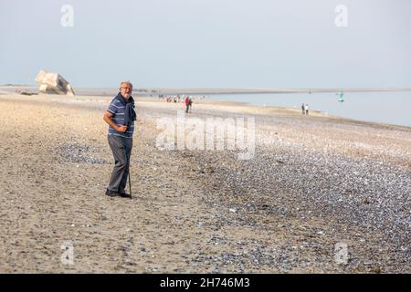 Älterer Mann, der mit seinem Stock am Strand von Hourdel läuft. Somme-Bucht, Frankreich Stockfoto