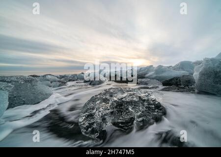 Ice Rock mit schwarzer Sandstrand Am Gletschersee Jökulsárlón Strand bei Sonnenuntergang. Diamond Beach im Südosten von Island. Stockfoto
