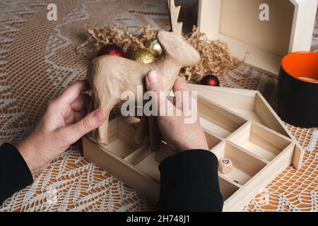 Minimales Öko Weihnachtskonzept. Damenhänden mit handgefertigten Dekorationen. Vorbereitung auf die Weihnachtsferien. Stockfoto