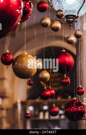 Weihnachtliche, rote und goldene Kugeln aus Glas hängen im Innenraum. Neujahrsdetails und festliche Atmosphäre Stockfoto