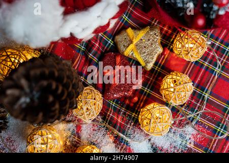 Goldene und rote Glocken, Tannenzapfen und Weihnachtslichter auf dem Weihnachtstisch Stockfoto