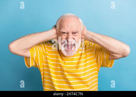 Porträt von attraktiven verrückten bösen Mann schließen Ohren Schreien isoliert über hellen blauen Hintergrund Stockfoto