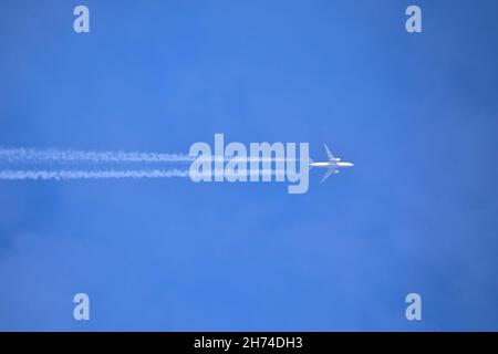 Ein Passagierjet und Dampf wandern gegen einen wolkenlosen blauen Himmel Stockfoto