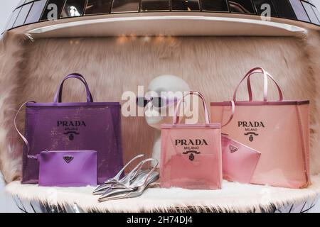 Lila und rosa Damen-Handtaschen, Sonnenbrillen und silberne High Heels in einem luxuriösen Schaufenster der italienischen Luxusmodemarke Prada Stockfoto