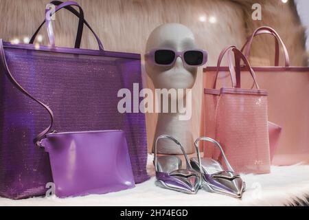 Lila rosa Damen-Handtaschen, Sonnenbrille, silberne High Heels in einem kreativen Ständer. Vorlage und Ort für Text weibliche Mode und Accessoires Stockfoto