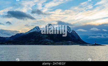 Landego Fyr, kleiner Leuchtturm auf einer Insel vor den mächtigen, schneebedeckten Bergen von Landegode, Norwegen. Postschiff - Kreuzfahrt im Herbst Stockfoto