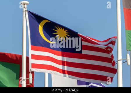 Malaysia Flagge hängt und weht in Sonnenschein auf blauem Himmel Hintergrund. Stockfoto