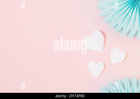 Romantischer rosa Pastellhintergrund mit Papierherzen und blauen Ornamenten, flaches Lay, Kopierraum Stockfoto