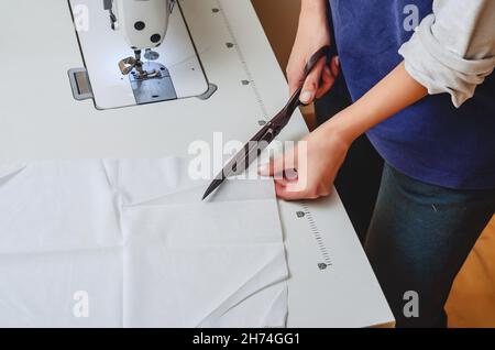 Vintage Schneiderschere geschnitten weißen Stoff. Frauenhände. Stockfoto