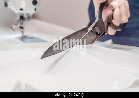 Vintage Schneiderschere geschnitten weißen Stoff. Stockfoto