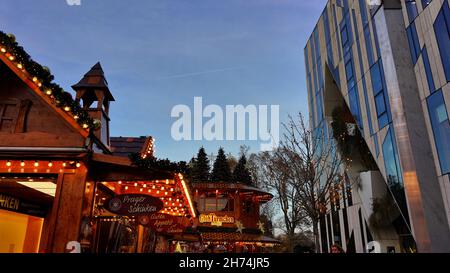 Traditioneller Weihnachtsmarkt steht auf dem Weihnachtsmarkt 2021 in Düsseldorf neben moderner Architektur des Kö-Bogen von Daniel Libeskind. Stockfoto