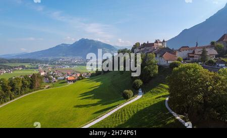 Luftaufnahme der Landschaft um die Altstadt von Gruyeres, mit der kleinen Stadt Bulle und den Bergen im Hintergrund. Gruyeres, Friburgo, Stockfoto