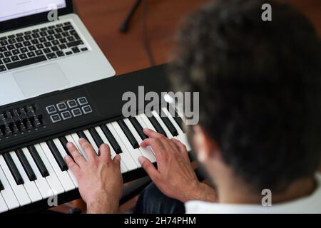 Musiker spielt Klavier vor seinem Computer Stockfoto