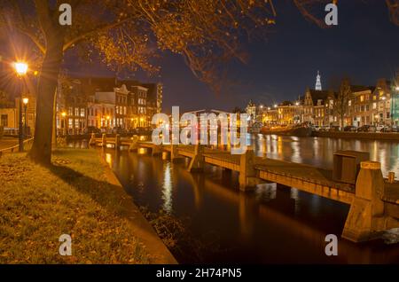 Haarlem, Niederlande, 19. November 2021: Blick auf die Altstadt bei Nacht mit einem Anlegesteg im Vordergrund und auf beiden Seiten der Spaarne im b Stockfoto