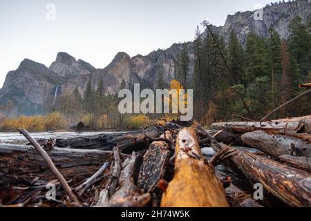 Low Angle Blick auf den Fluss durch das Yosemite Valley mit großen Bergen und Wasserfall im Hintergrund Stockfoto