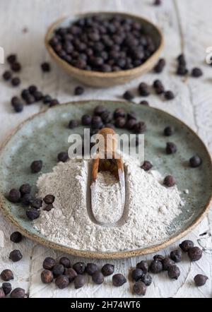 Teller und Holzlöffel aus schwarzem Kichererbsenmehl und Bohnen lassen sich auf dem weißen Holztisch verstauen. Traditionelle Bohnen aus Apulien und Basilikata in Italien Stockfoto