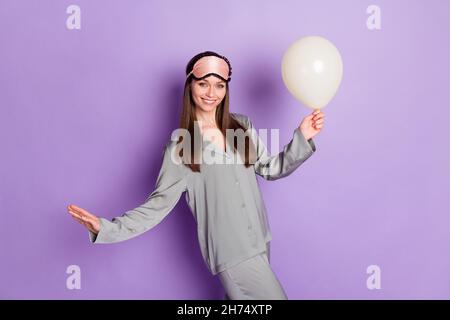 Foto-Porträt des Mädchens in Pyjama Schlafmaske halten Ballon Vorbereitung auf Geburtstag isoliert auf pastelllila Farbe Hintergrund Stockfoto