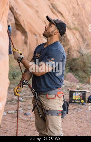 Ein Kletterer, der einen anderen Kletterer bei der Besteigung einer Felswand im Klettergebiet der Wall Street in Moab, Utah, abstellt. Stockfoto