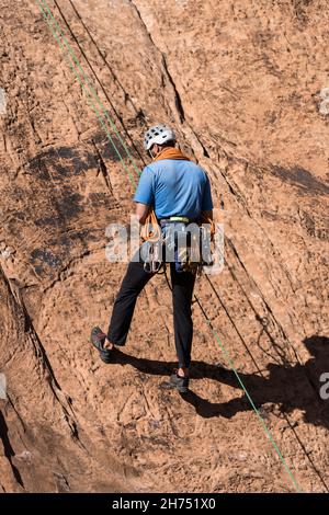 Ein Bergsteiger steigt die Mauer, die er gerade an der Wall Street in der Nähe von Moab, Utah, bestiegen hat. Stockfoto