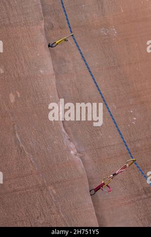 Das Kletterseil, das durch eine schnelle Kletterroute führt, zieht einen Riss auf einer Kletterroute in Utah ein. Stockfoto