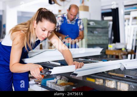 Arbeiterinnen schneiden Metall-Kunststoff-Profile in der Werkstatt, mit Zangen Stockfoto