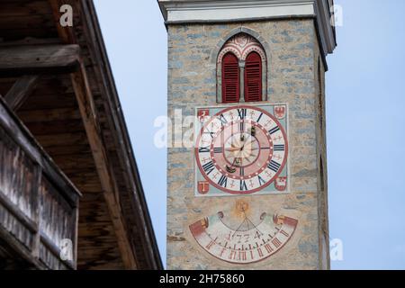 NATZ-SCHABS, ITALIEN - 13. OKTOBER 2019: Vor kurzem restaurierte Uhr und Sonnenuhr, die vor dem Glockenturm der Kirche der Stadt gemalt wurde. Stockfoto