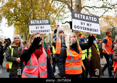 London, Großbritannien. 20th. November 2021. Aktivisten halten während der Demonstration Plakate. Die Aktivisten der Beleidigung Großbritanniens marschierten in Solidarität mit den neun Aktivisten, die wegen einer Verfügung inhaftiert wurden, indem sie am 8th. Oktober an der Blockade an der Kreuzung 25 der M25 teilnahmen, um die Regierung aufzufordern, die Isolierung von sozialem Wohnungsbau bis 2025 und aller Häuser zu finanzieren In Großbritannien bis 2030. Der marsch begann am Königlichen Gerichtshof um 12pm Uhr und Aktivisten sind bereit, zivilen Ungehorsam in der Stadt zu verursachen. Kredit: SOPA Images Limited/Alamy Live Nachrichten Stockfoto