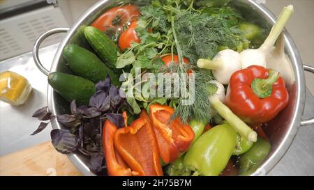 Frisches Rohes Frühlingsgemüse. Clip. Essen Vegetarisch Hintergrund. Tomaten, Gurke, Radieschen, Salatblätter im Metallkorb. Draufsicht Stockfoto