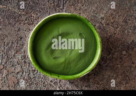 Grünes Chlorella-Algenpulver in einer Schüssel auf dunklem Hintergrund, Draufsicht Stockfoto