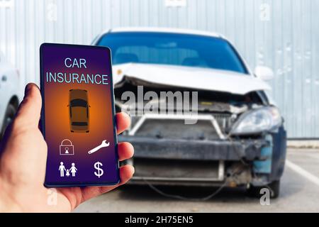 Schöner Mann Hand hält Smartphone, um Auto-Versicherung Anwendung online nach seinem kaputten Auto zu verwenden. Versicherungskonzept. Stockfoto
