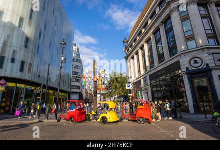 Bunte Fahrradtaxis parken in der Wardour Street am Eingang zum Leicester Square im West End von London Stockfoto