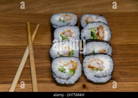 Japanisches Sushi-Essen auf Holzhintergrund. Maki und Brötchen mit Thunfisch, Huhn, Avokado und Gurke Stockfoto