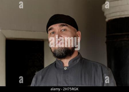 Porträt eines ernsthaften älteren asiatischen Mannes mit Totenkopfkappe. Blick auf die Kamera Stockfoto